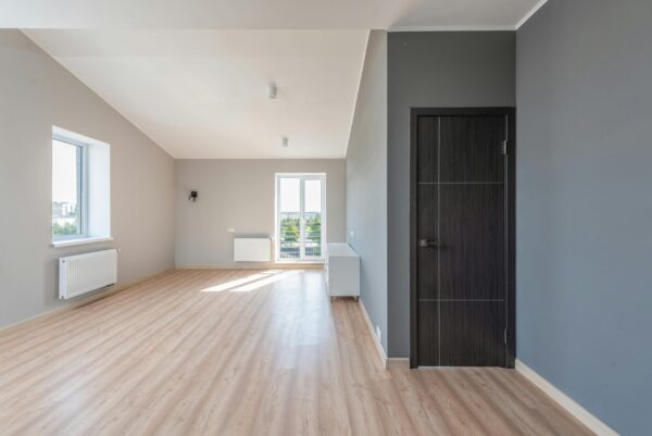 Bright interior of a spacious room with wooden flooring and large windows